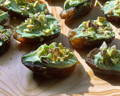 A group of soft deglet noor dates stuffed with bright green matcha cream cheese, sprinkled with pistachio bits.