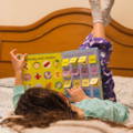 Child lying in bed and reading an educational colorful children's book.