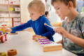 Two boys playing with a wooden xylophone in a Montessori classroom.