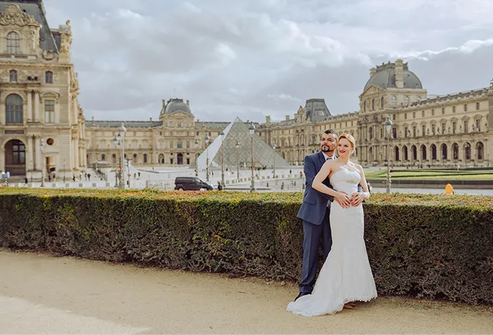 Photo de la mariée blonde dans une robe de mariée sirène Pronovias, avec son mari brun portant un costume bleu marine.