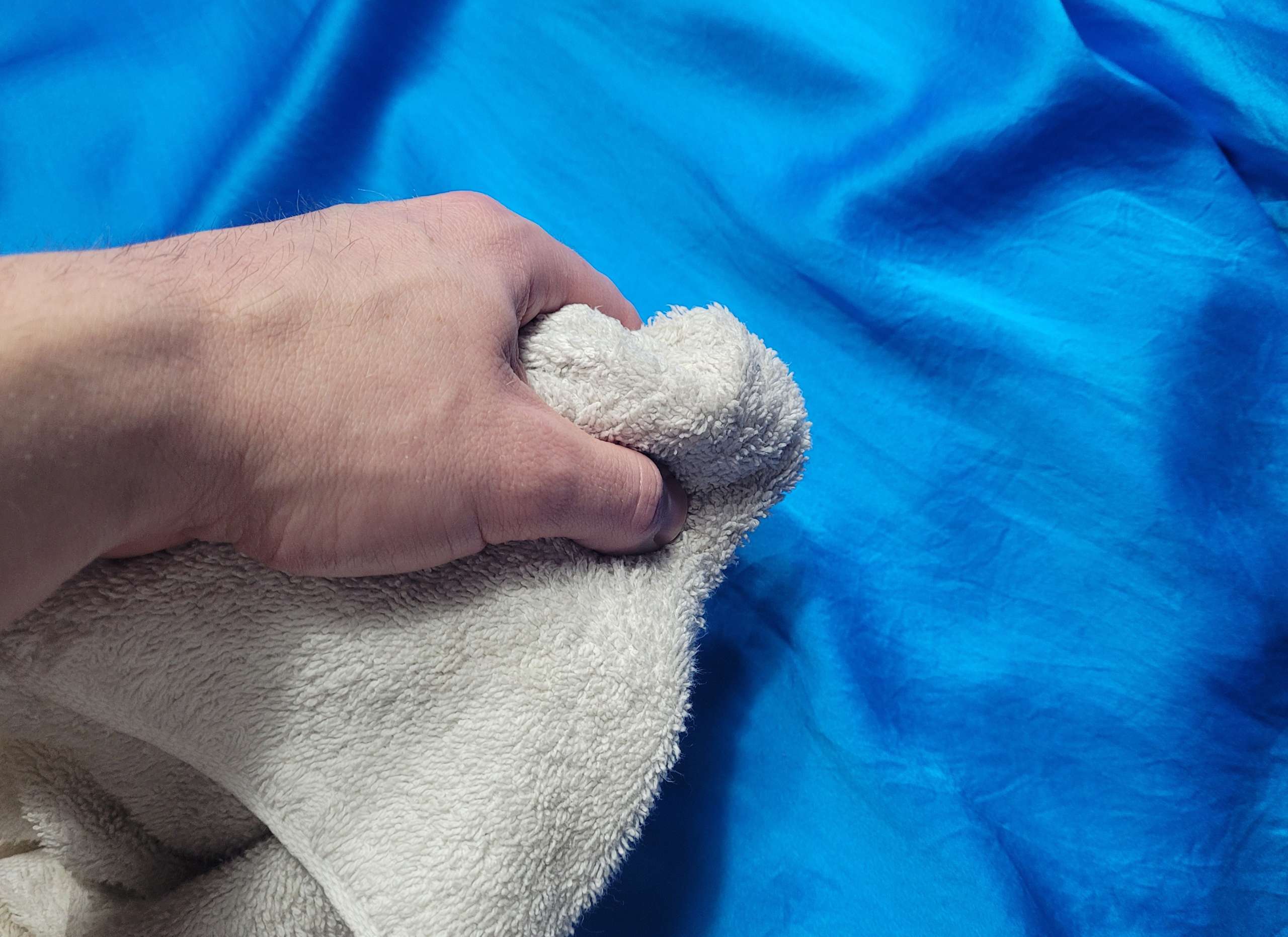 photo of a person using a damp white cloth to test satin pajamas for colorfastness