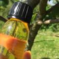 Modern Botany Multi-tasking Oil 60ml held against a backdrop of a tree on a sunny day.