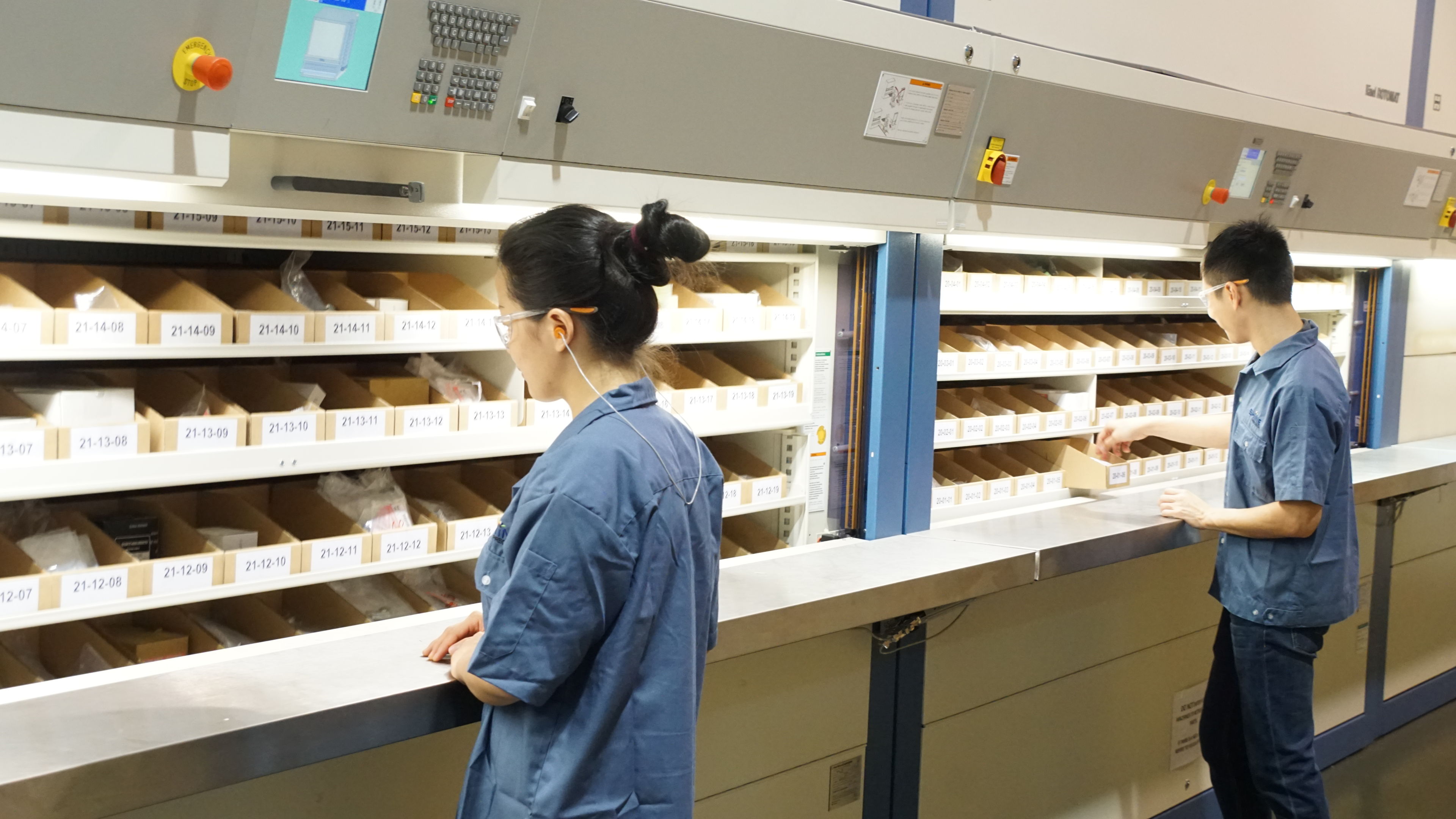 Two staff picking parts from a storage system