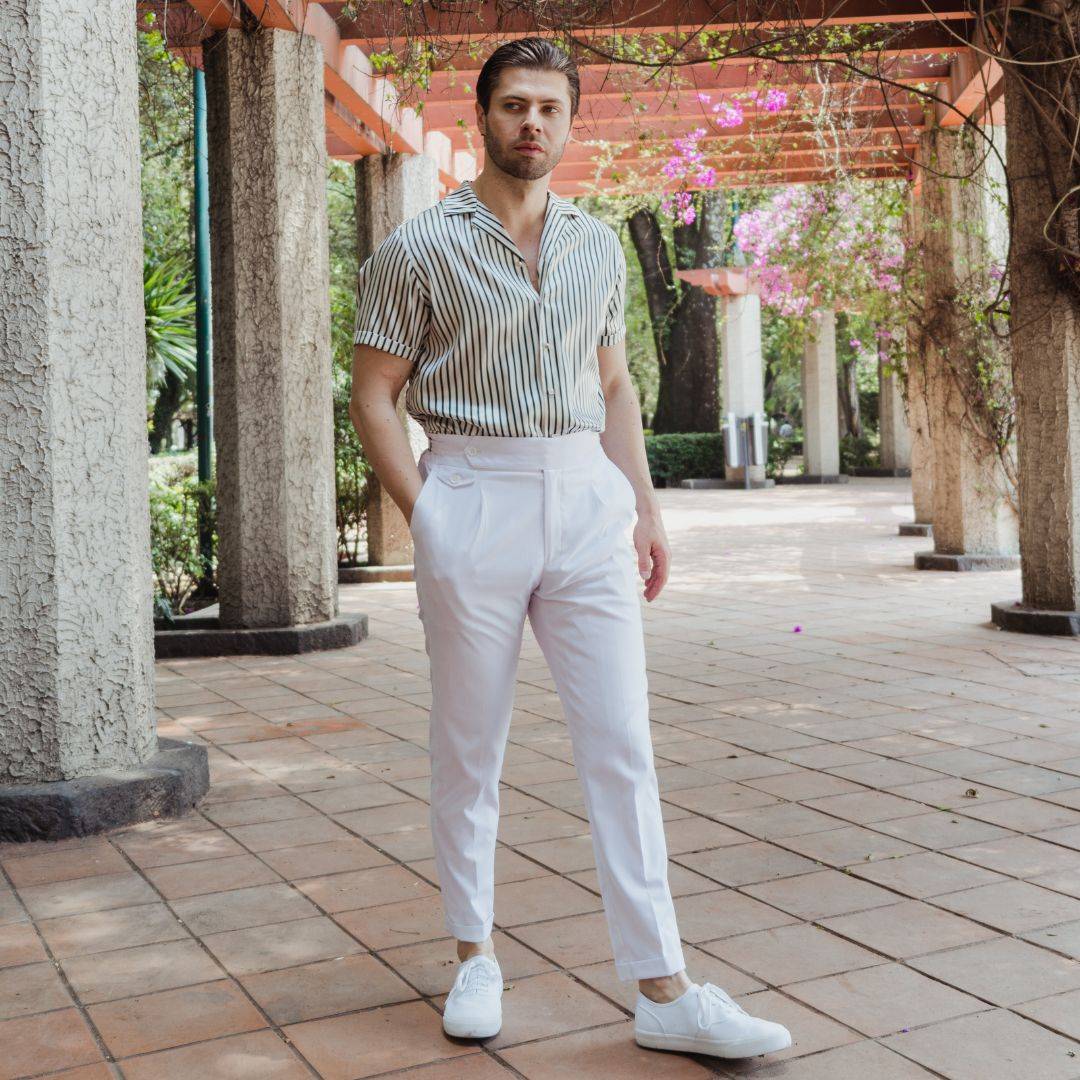 man wearing a green stripe silk shirt with white high waisted pants and white shoes