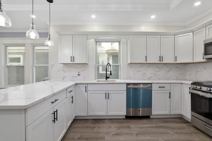 kitchen featuring stainless steel dishwasher, range oven, microwave, light countertops, white cabinetry, dark hardwood floors, and pendant lighting