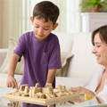 Little boy and his mother playing a wooden dice and numbers game in the living room.