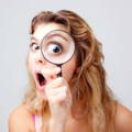 Woman looking through magnifier in shock