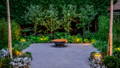 Sculpted greenery and layered copper spike lighting create depth and softness throughout the landscape by Havit Lighting.