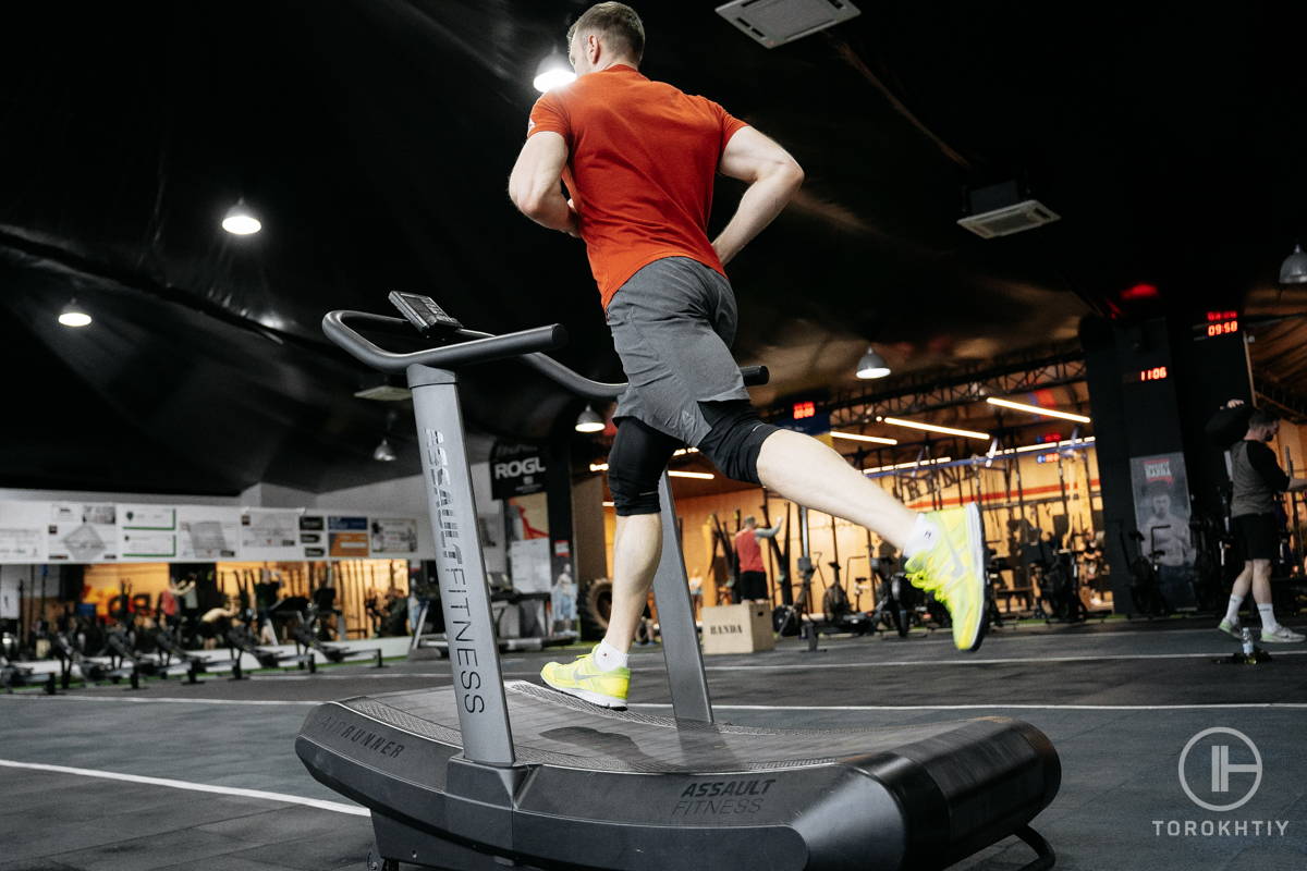 athlete in orange running left on treadmill
