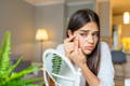 Woman trying to pop a pimple on her skin with acne