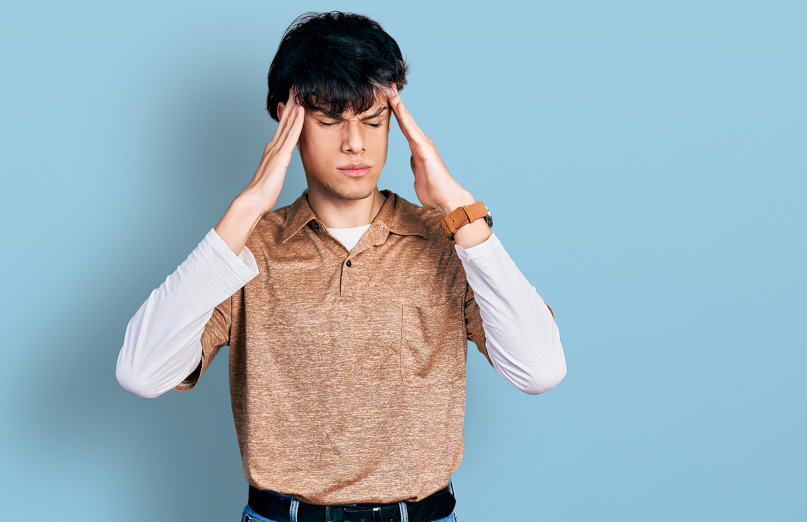 mage of a young hipster guy wearing 90s long sleeve shirt and collar shirt, with his hands on his head looking frustrated.