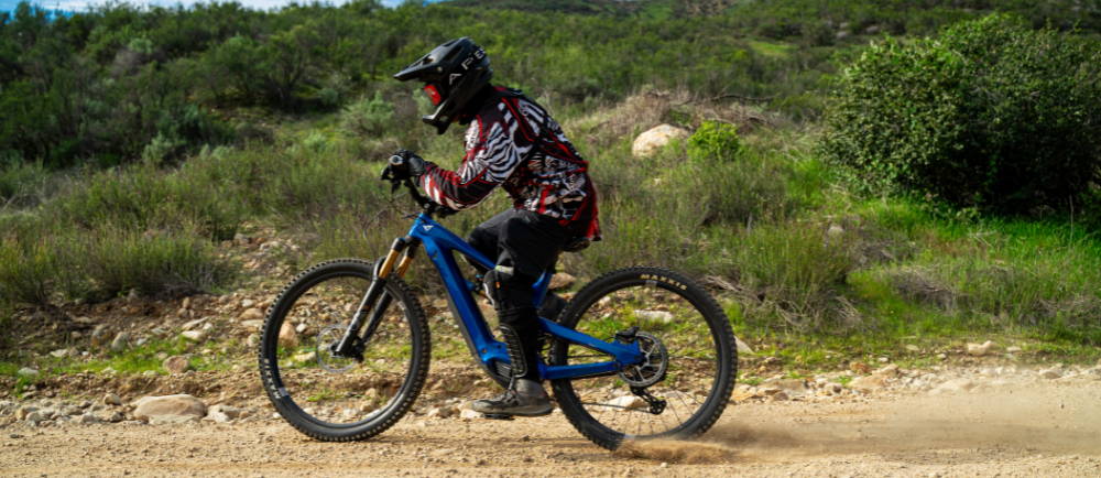 a man riding a blue full suspension electric mountain bike in the wilderness