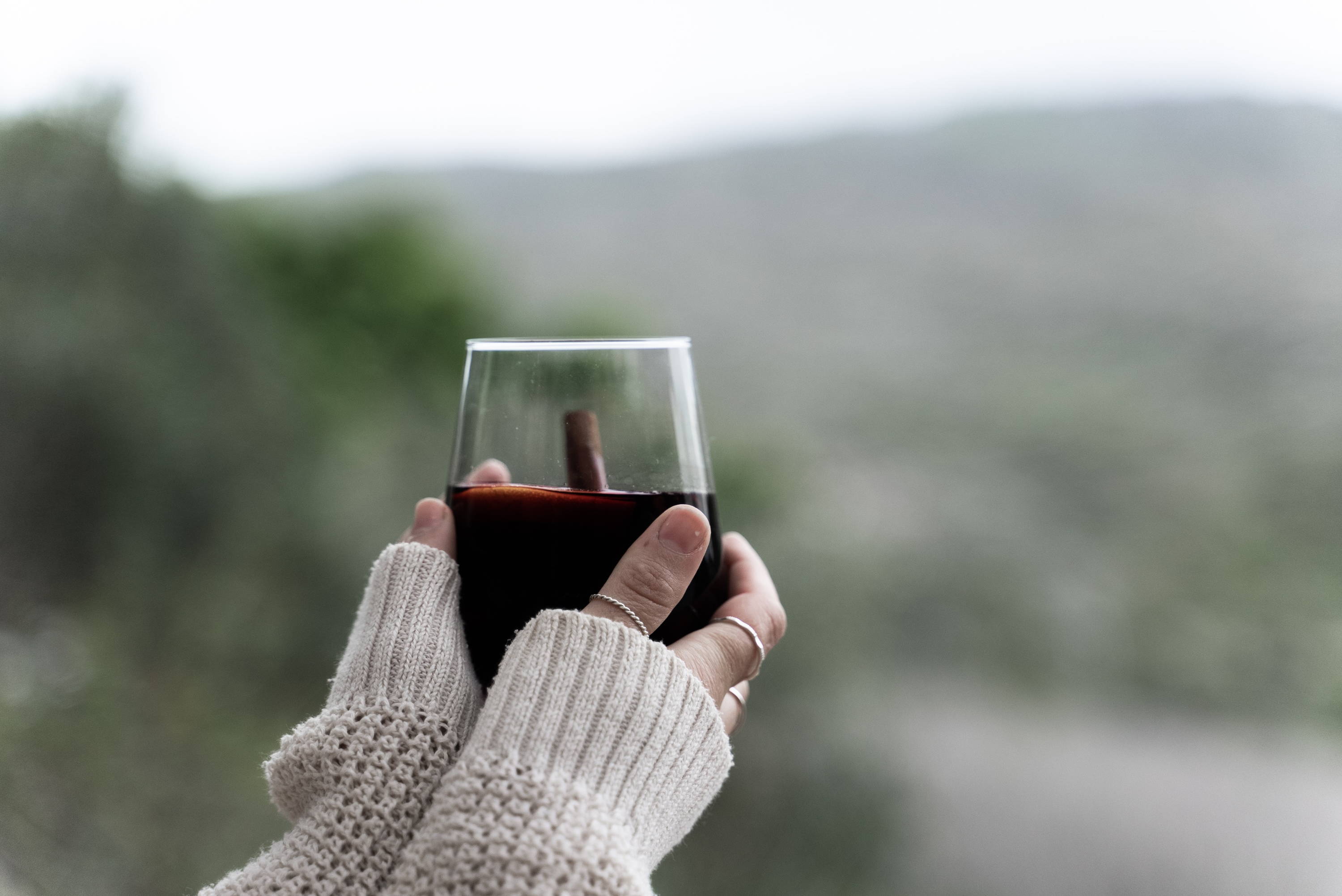Women's arm holding a glass of rich red wine seen by its full-bodied appearance. 