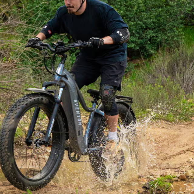 a man riding an aventon fat tire electric bike through a puddle