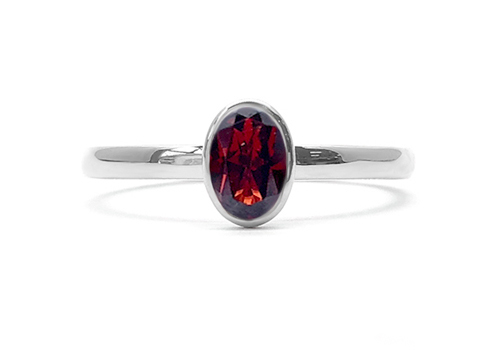 White gold ring with an oval garnet in closed setting. 