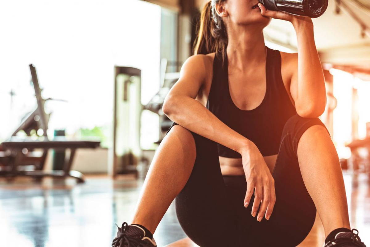 woman drinking pre-workout at gym