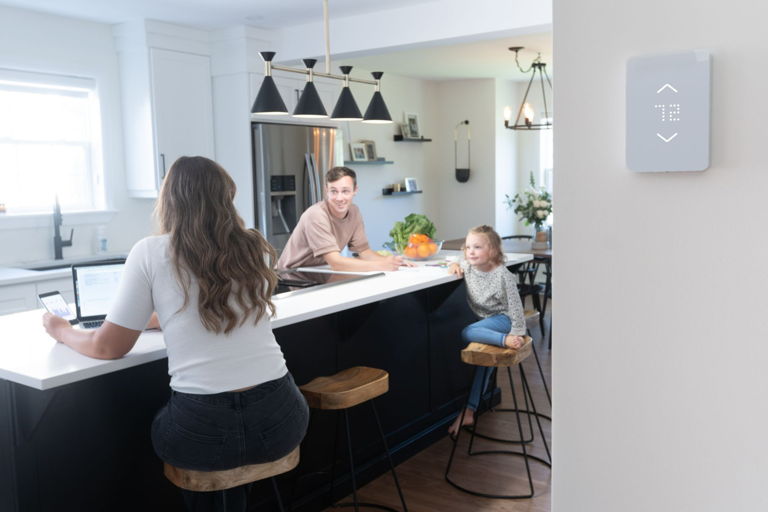 Une famille vérifie les informations sur l’énergie du thermostat intelligent pour plinthes chauffantes