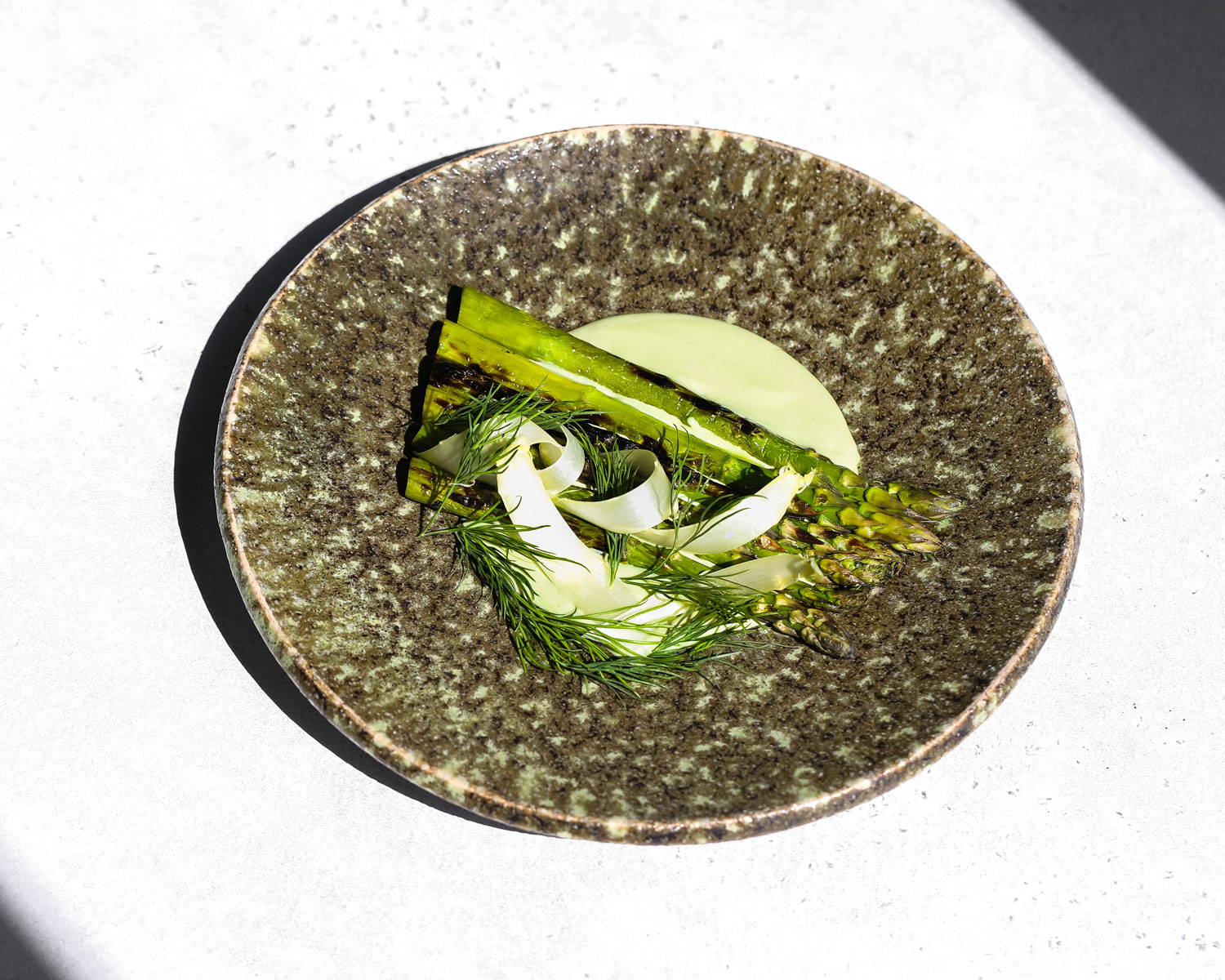 Tofu matcha sauce accompanying spears of asparagus, garnished with sprigs of fennel