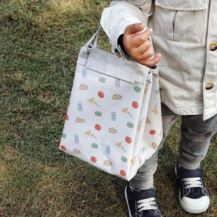 Little boy holding a bag that turns into a blanket of a Picnic Set.