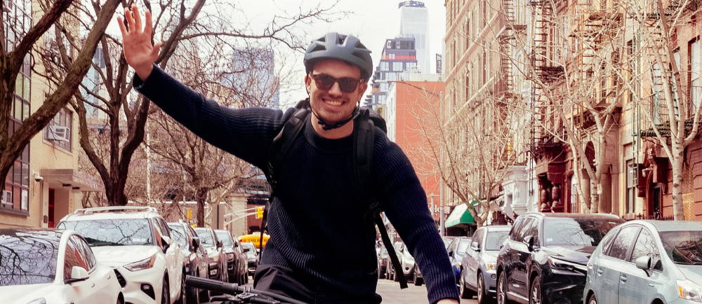 a man waving while riding a bike