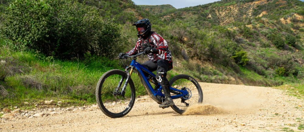 a person riding a blue full suspension electric mountain bike in the wilderness