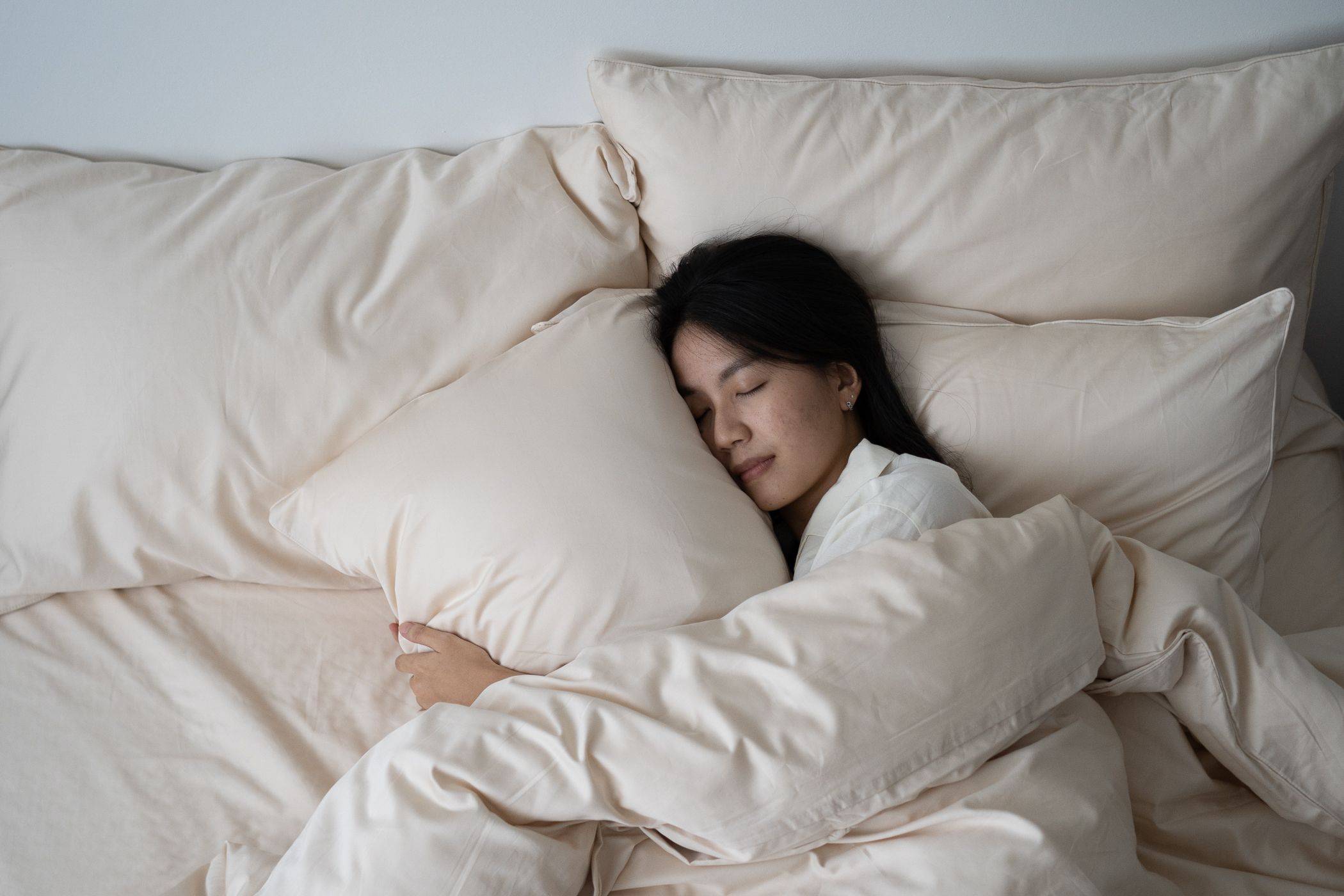 girl sleeping on side hugging pillow under Weavve's cotton bed sheets