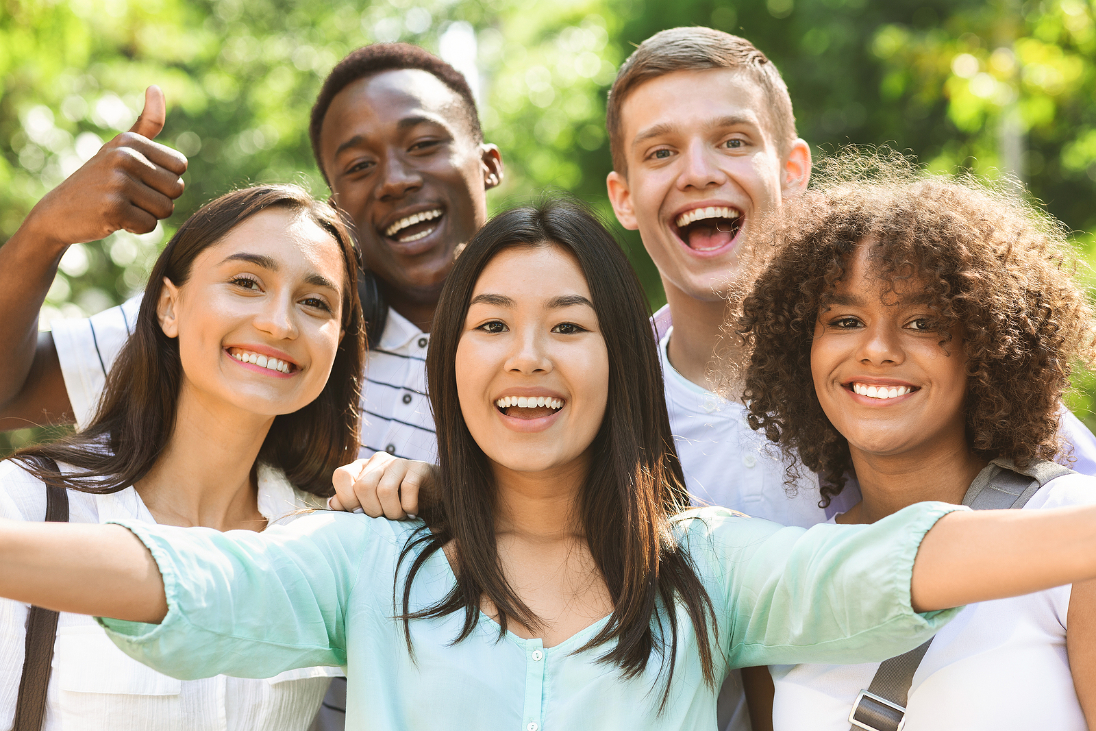 An attractive group of friends pose together while the friend takes a picture of all of them.