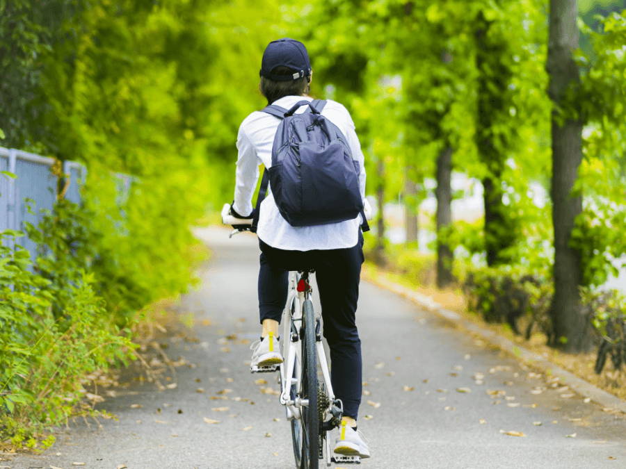 歩道で自転車に乗る女性の後ろ姿