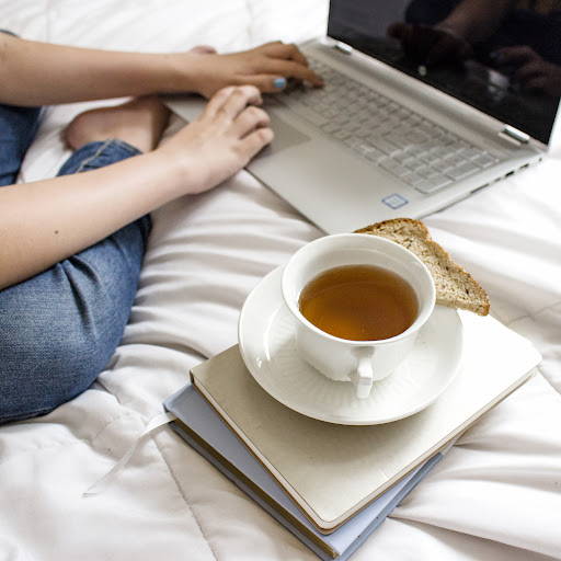 A person using a laptop next to a cup of coffee