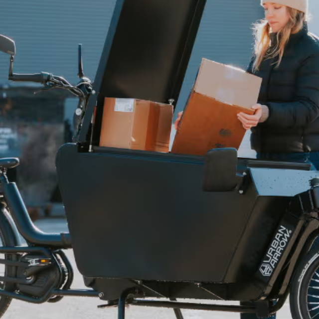 a woman putting a box in a front loader electric cargo bike