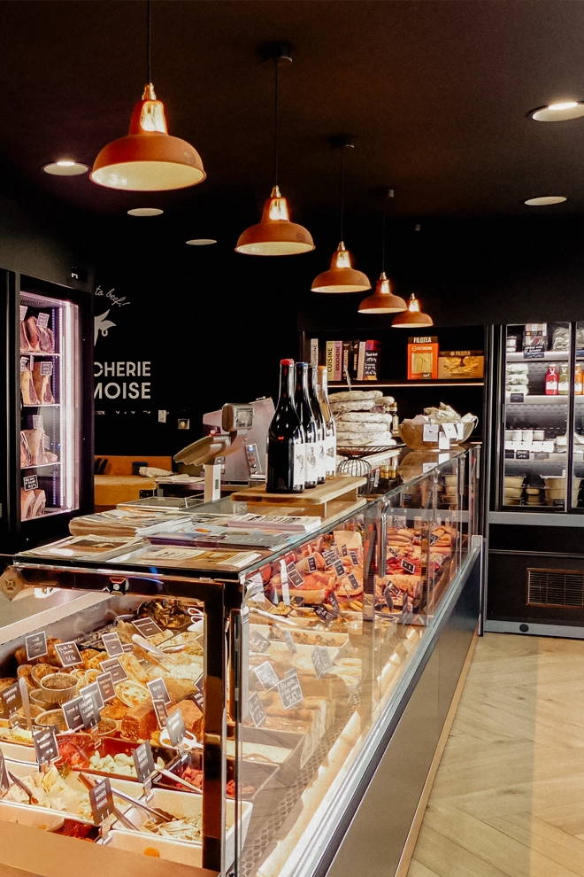 A row of Natural Terracotta Coolicon lampshades hanging over a retail counter in a French Butchers
