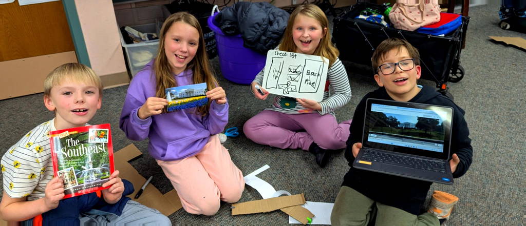 4 students holding up magazines and research documents for the landmark project