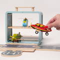 Woman's hand interacting with a wooden airplane with the Montessori Airplane set visible in the background. 
