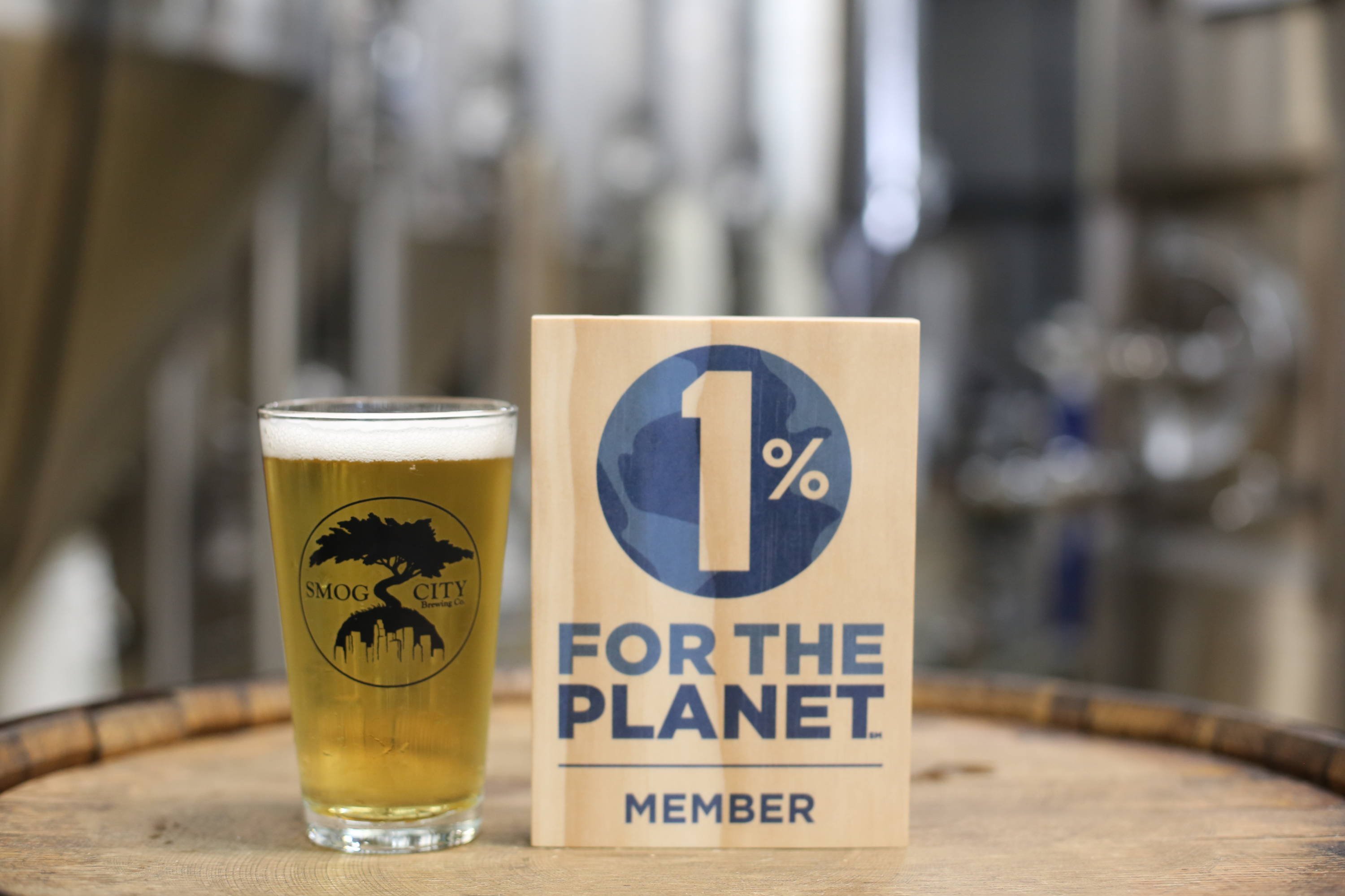 Pint of beer next to a wooden 1% for the Planet sign