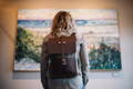 woman wearing the lookout daggett pack looking at a painting of trees and water