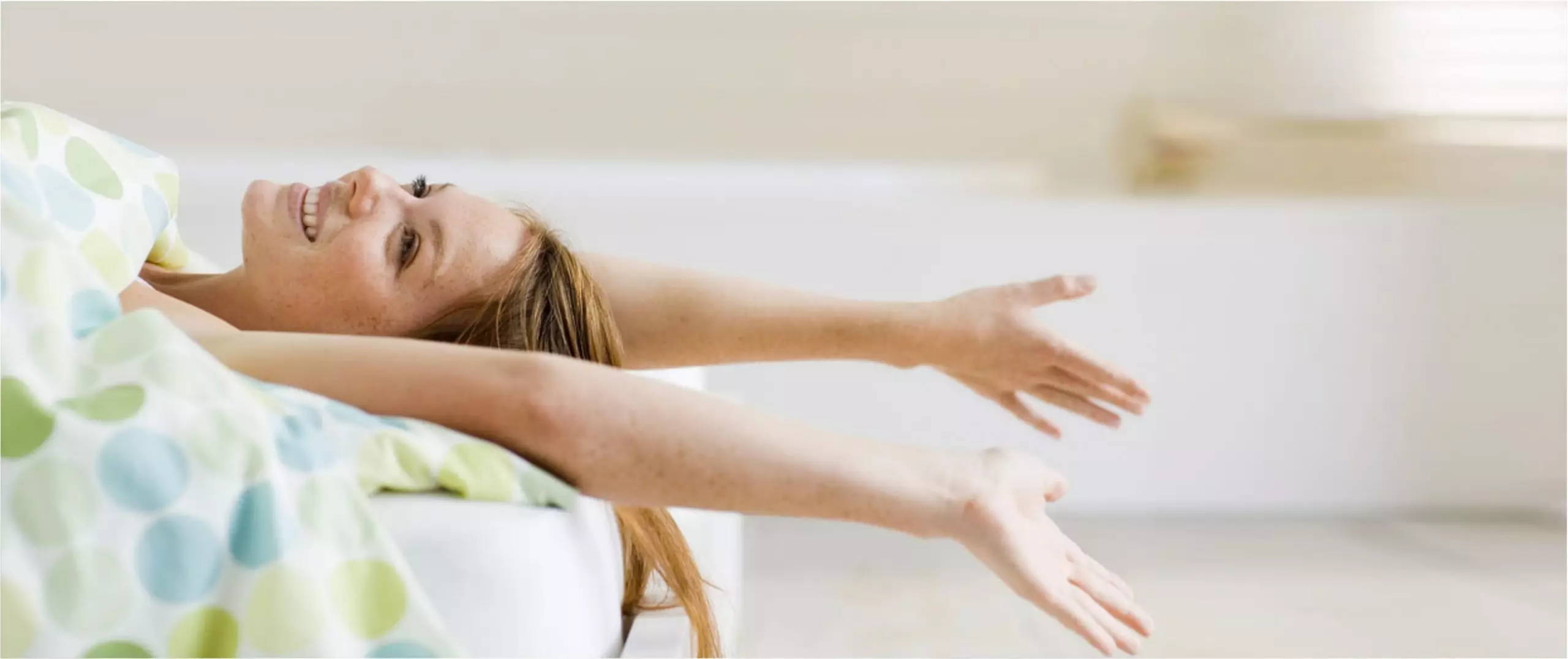 red-haired woman stretching off the end of her bed after taking cbd products for sleep