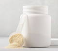 plain white jar of collagen protein powder with full scoop leaning against the jar