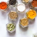 Several small glass spice jars with their lids of sit filled with various different spices