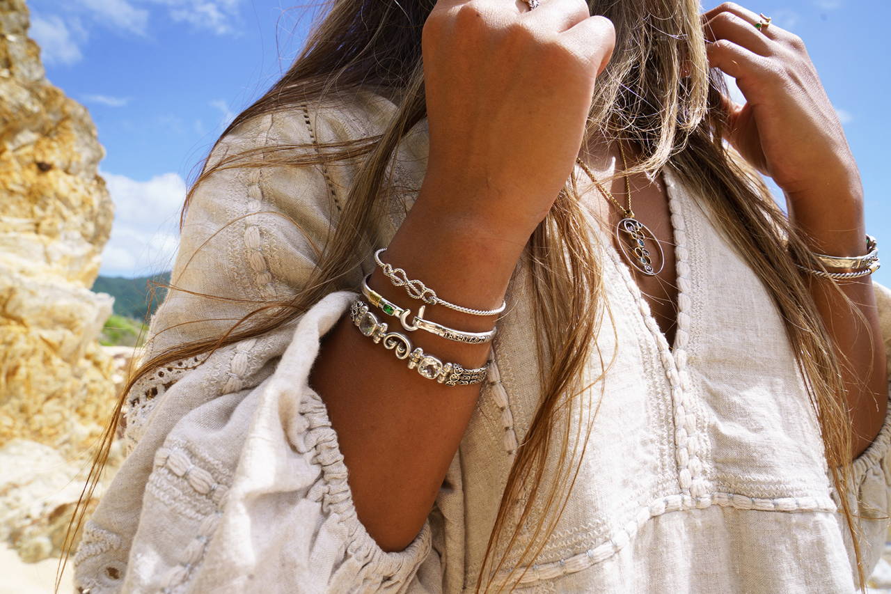 A woman showing her jewelry style with many bracelets and a necklace