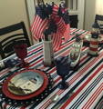 red, white and blue striped tablecloth on a table decorated with lighthouses and a ship, with a lot of american flags