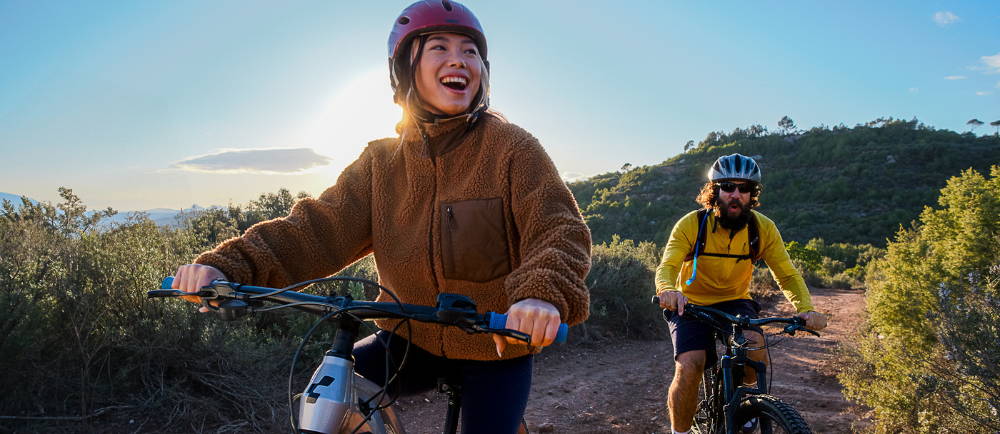 A couple riding e-MTBs on a trail