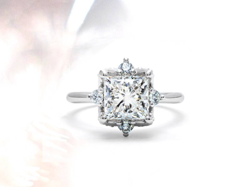 High jewellery ring in white gold with a princess diamond in the centre and four small diamonds around it.