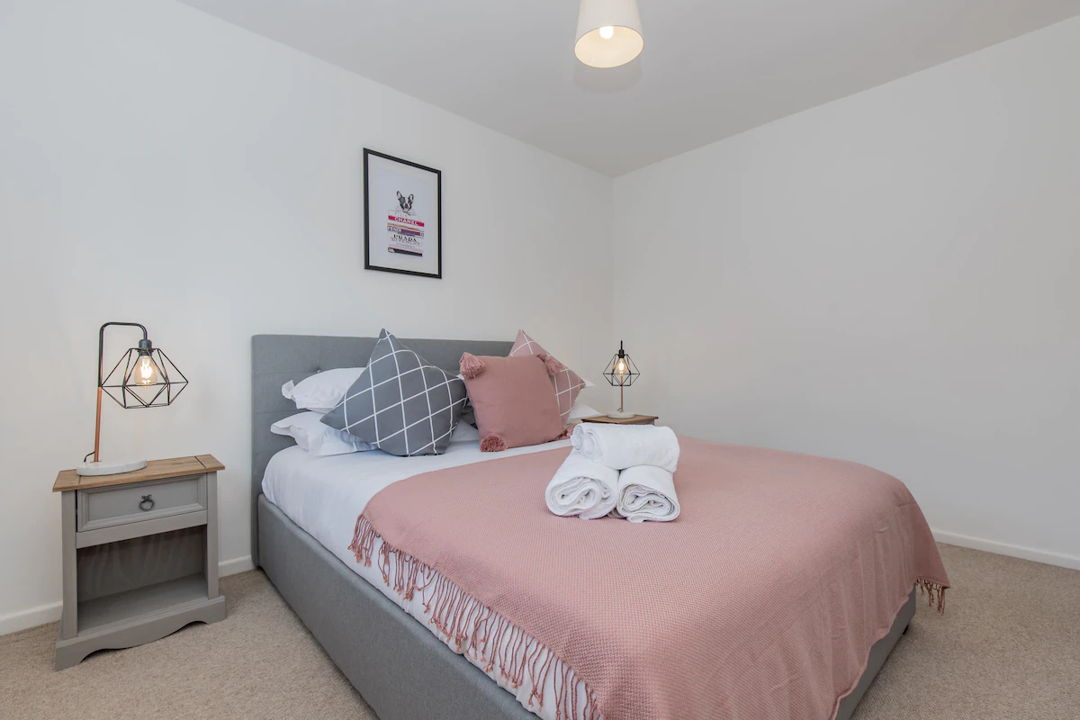 Bedroom with large queen size bed with a large pink throw