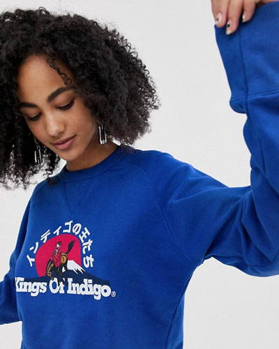 Close up of woman wearing bright blue organic cotton sweatshirt with printed design across the chest