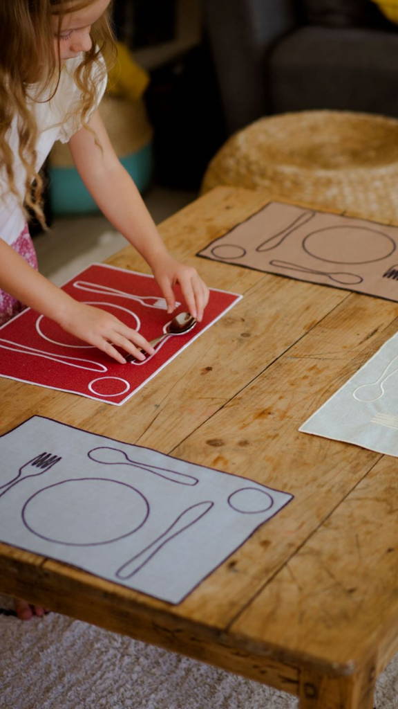 Une petite fille installe le couvert dans un grâce à un kit d'activité Montessori