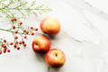 3 apples on a marble white top with cherries in the background