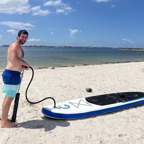 Boy inflates his SUP paddle board with manual pump for inflatable paddle board