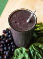 a glass of blueberry and peanut butter green smoothie - a great way to cover the green taste of wheat grass powder