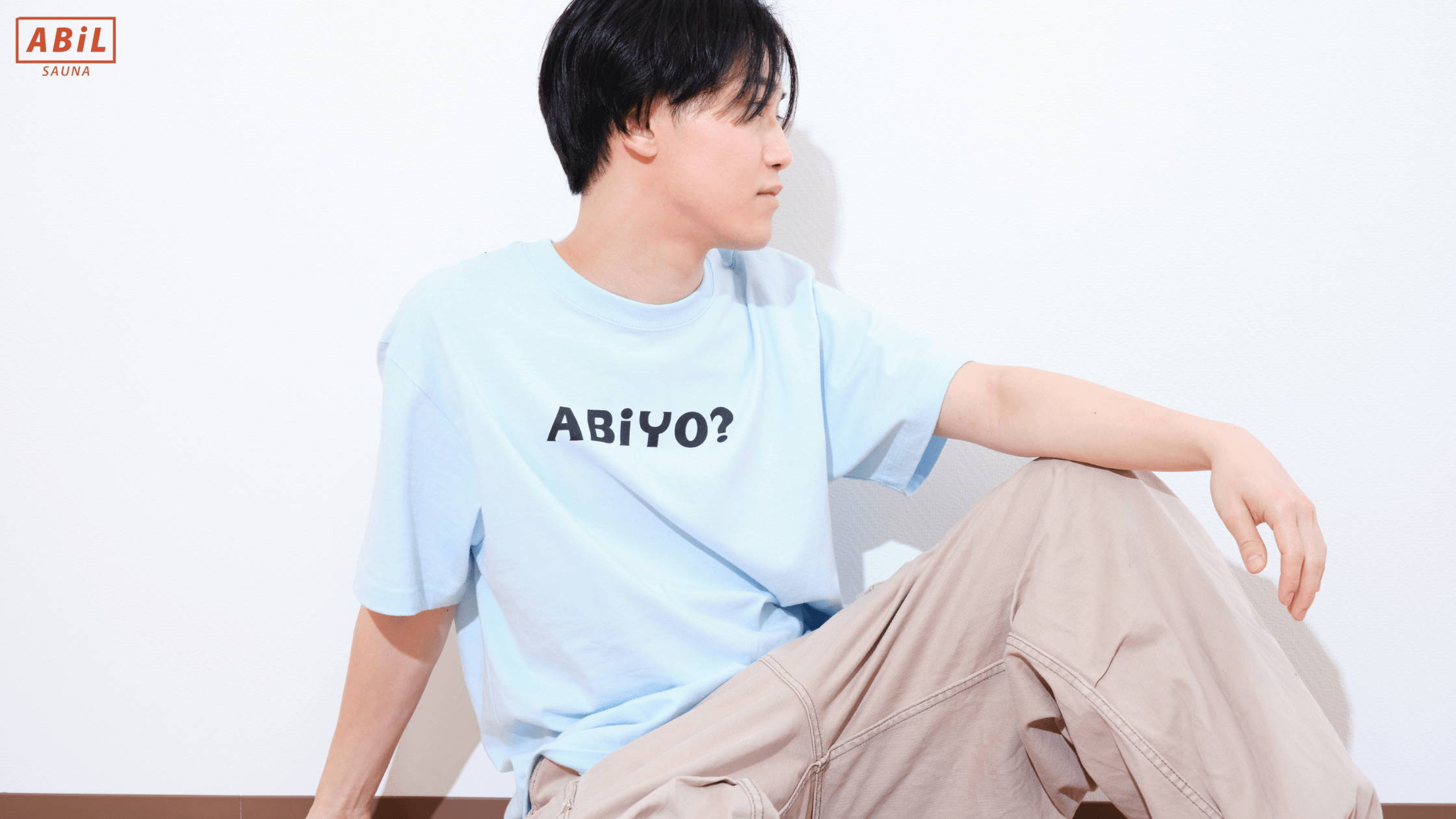 夏にぴったりなABiLのABiYO? Tシャツを着た男性モデルの着用イメージ外気浴スペースで目を閉じて“ととのい”を感じている女性