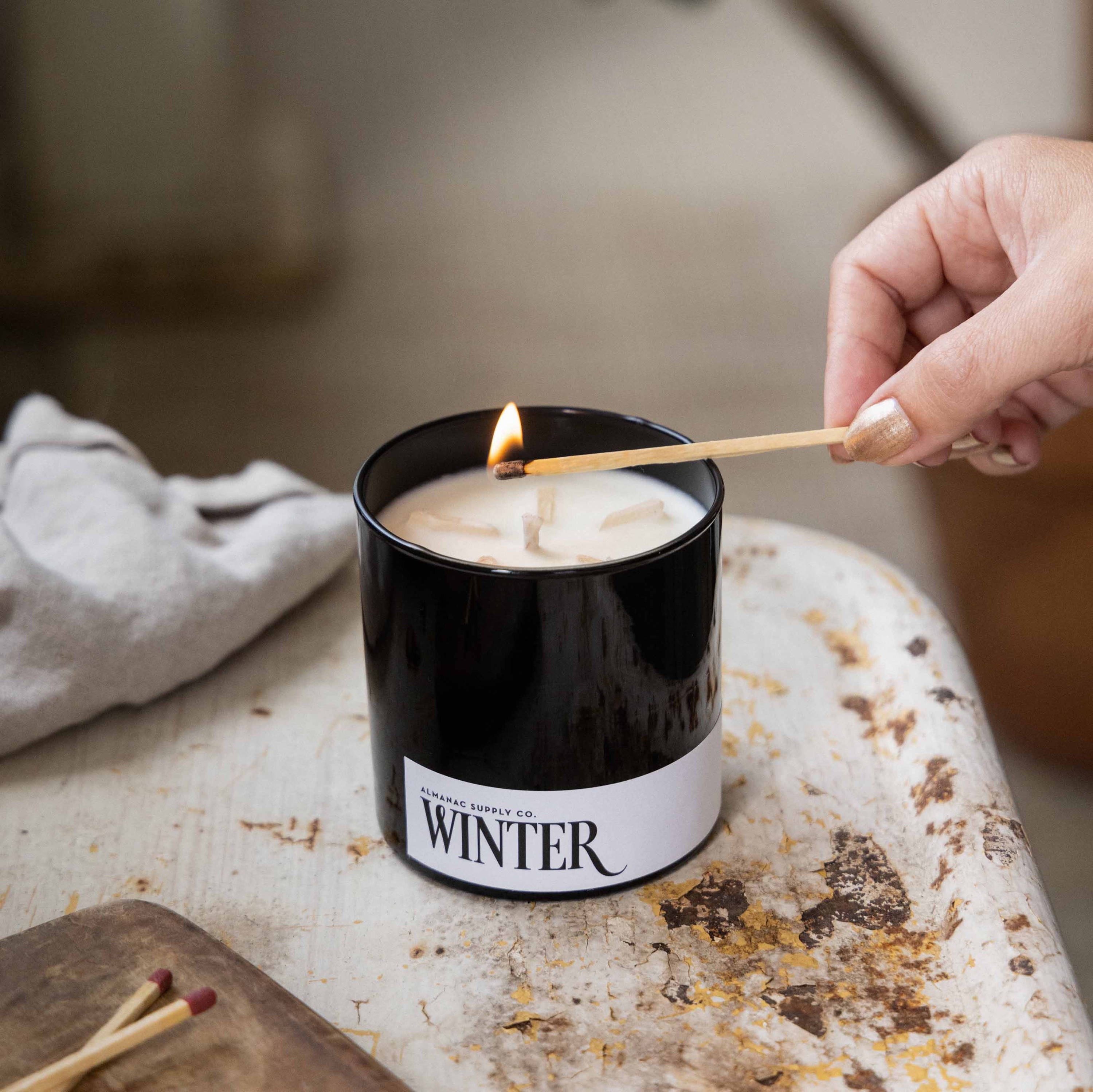 Winter candle in black jar with long match and flame